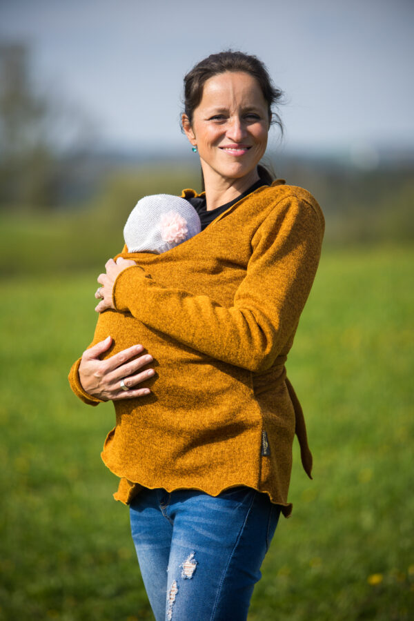maminka, která nese miminko v zavinovacím svetru pro nošení miminka v šátku nebo nosítku