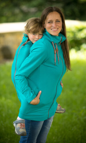 babywearing maminka s dítětem, které nese na zádech v nosítku a nosicí mikině zn. Angel Wings tyrkysové barvy