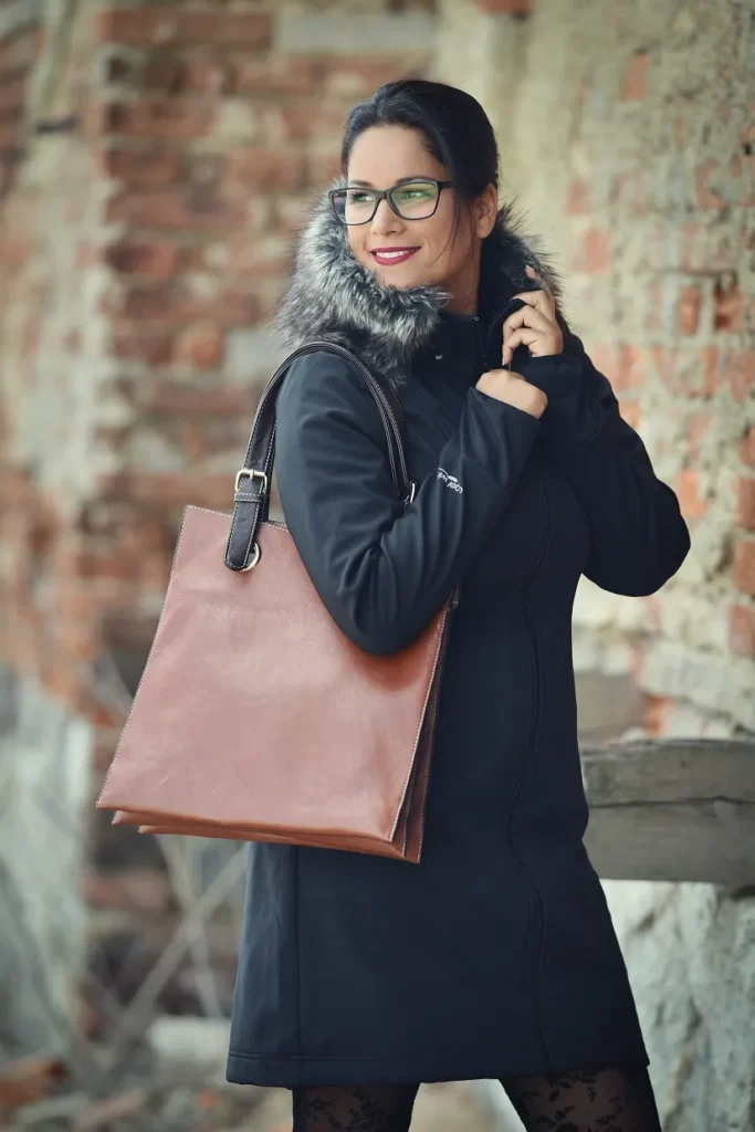 žena v brýlích zapíná elegantní černý softshellový kabát pro nošení dětí
